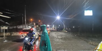 Hujan Mengguyur, Bhabinkamtibmas Desa Lingga Tetap Siaga Atur Lalu Lintas di Jalan Lintas Sumatera